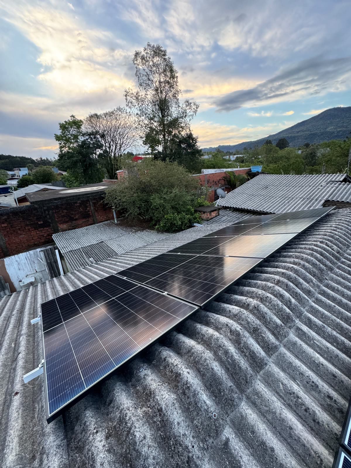 Painéis solares instalados num telhado de fibrocimento, ao pôr do sol
